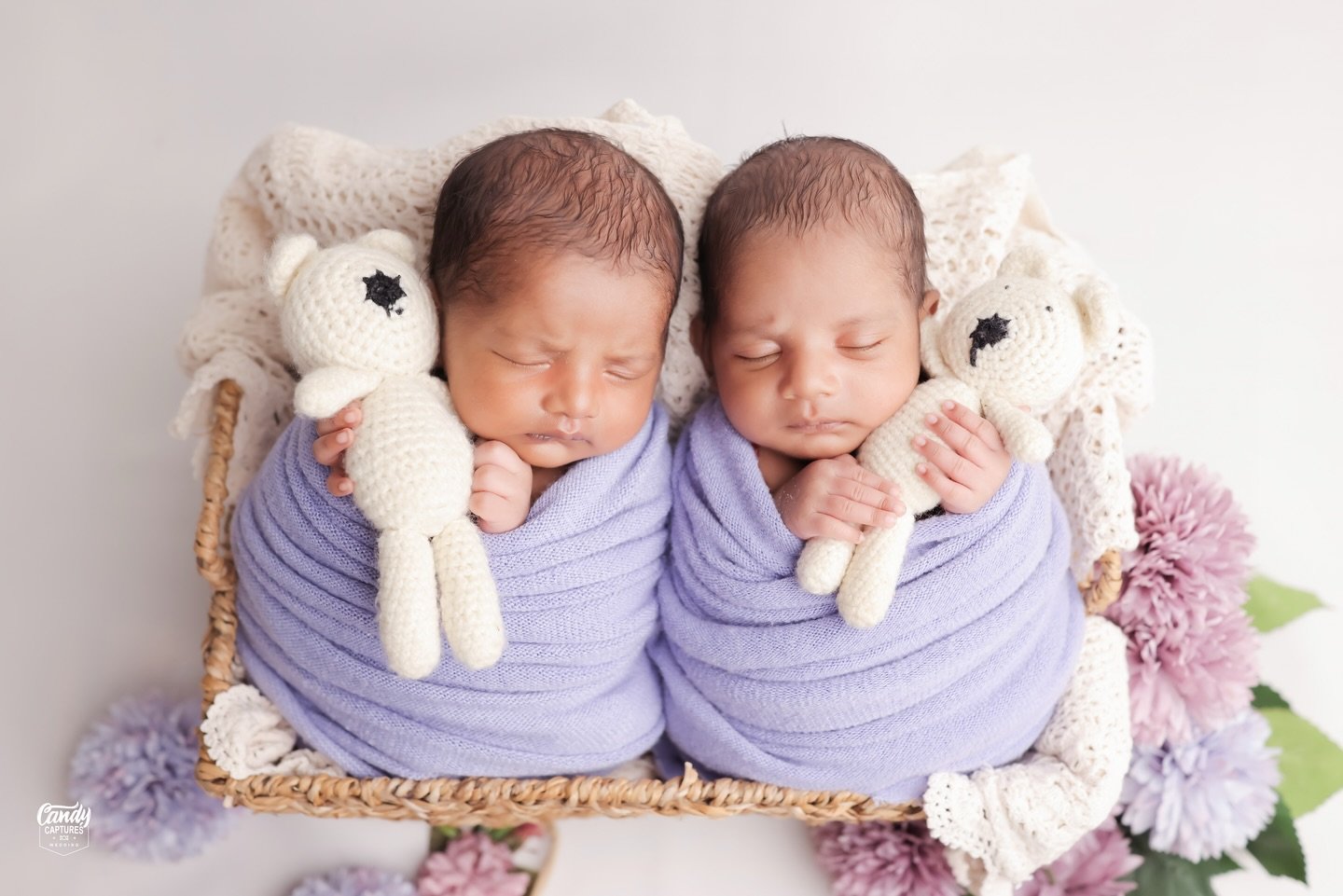 Newborn twins sleeping side by side with tiny toys